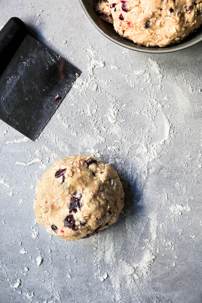 The oatmeal cookie dough on a lightly floured surface in a ball shape with the other half in a bowl