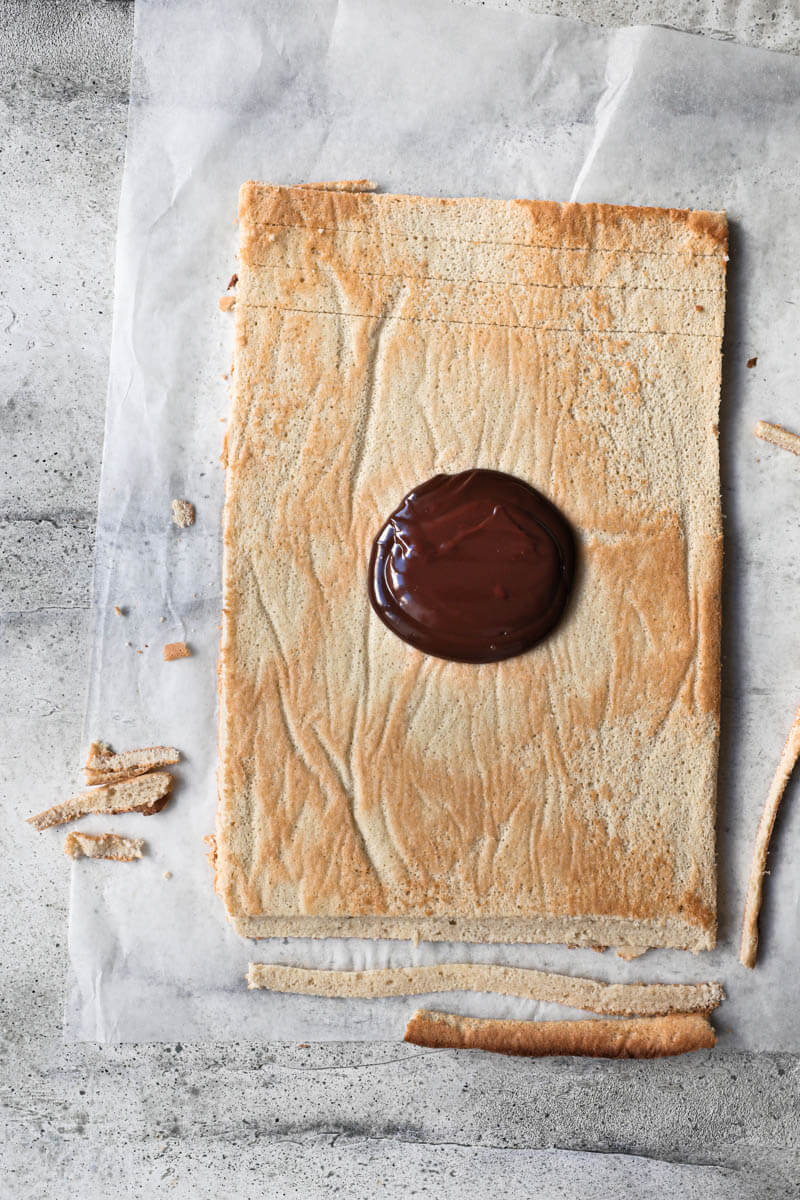 Roll cake on a piece of parchment paper with chocolate ganache at the centre