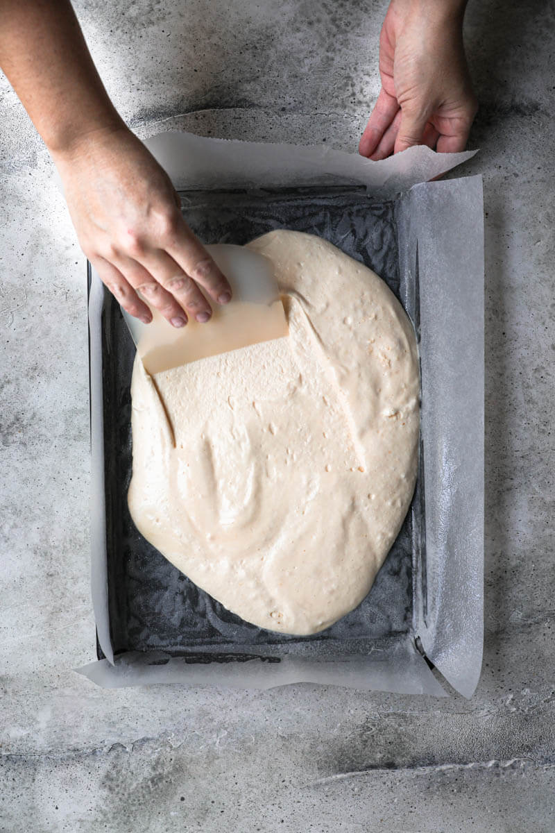 Hand spreading the cake batter using a pastry horn