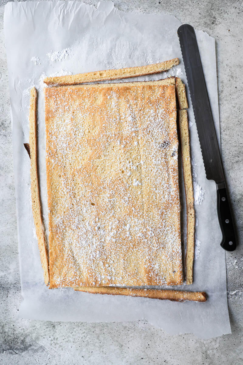 Baked roll cake inverted onto a piece of parchment paper with the edges cut off