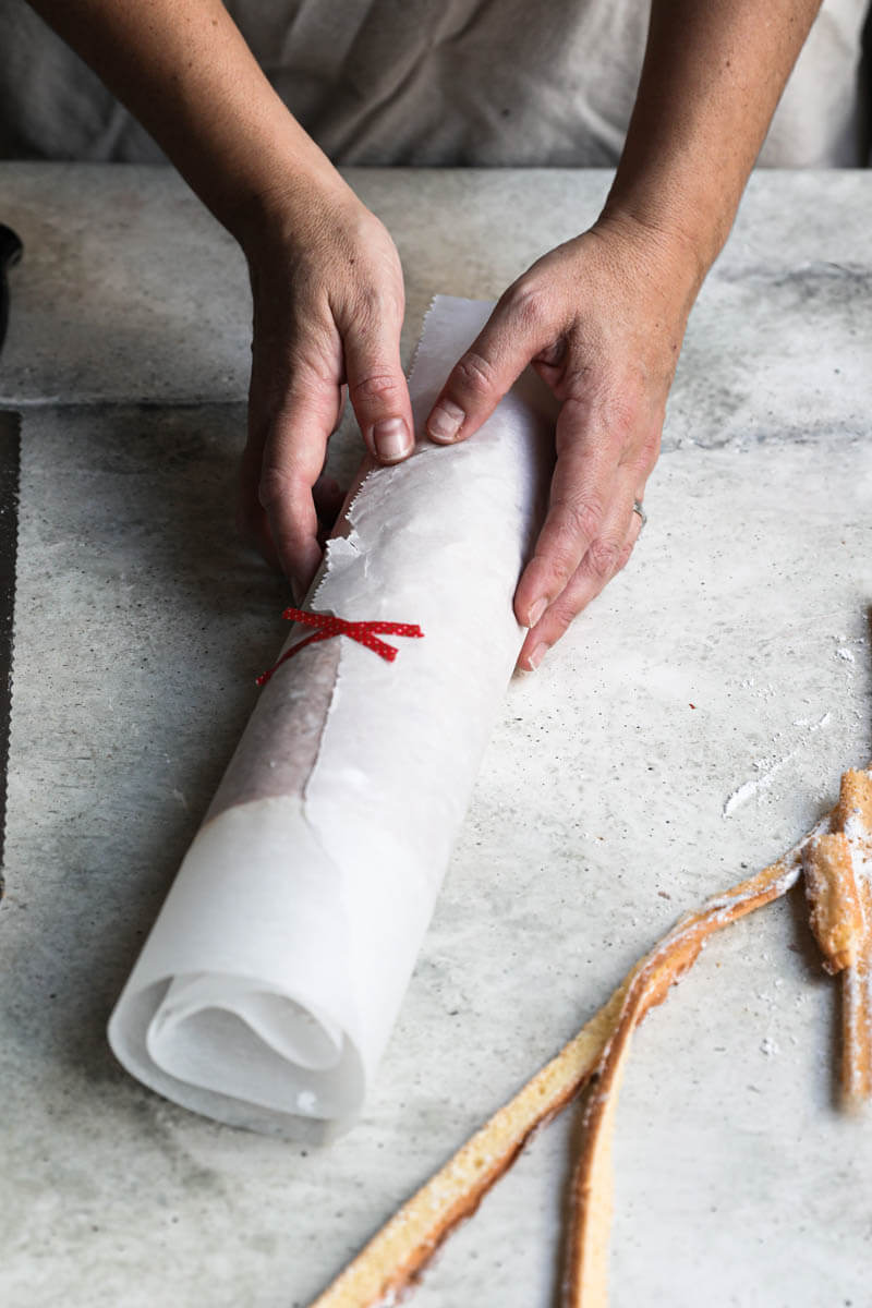 Log cake covered in parchment paper cooling off