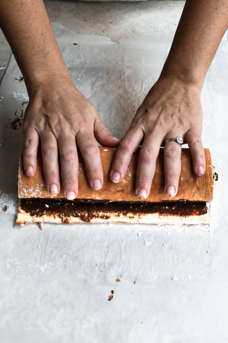 Two hands rolling the filled cake