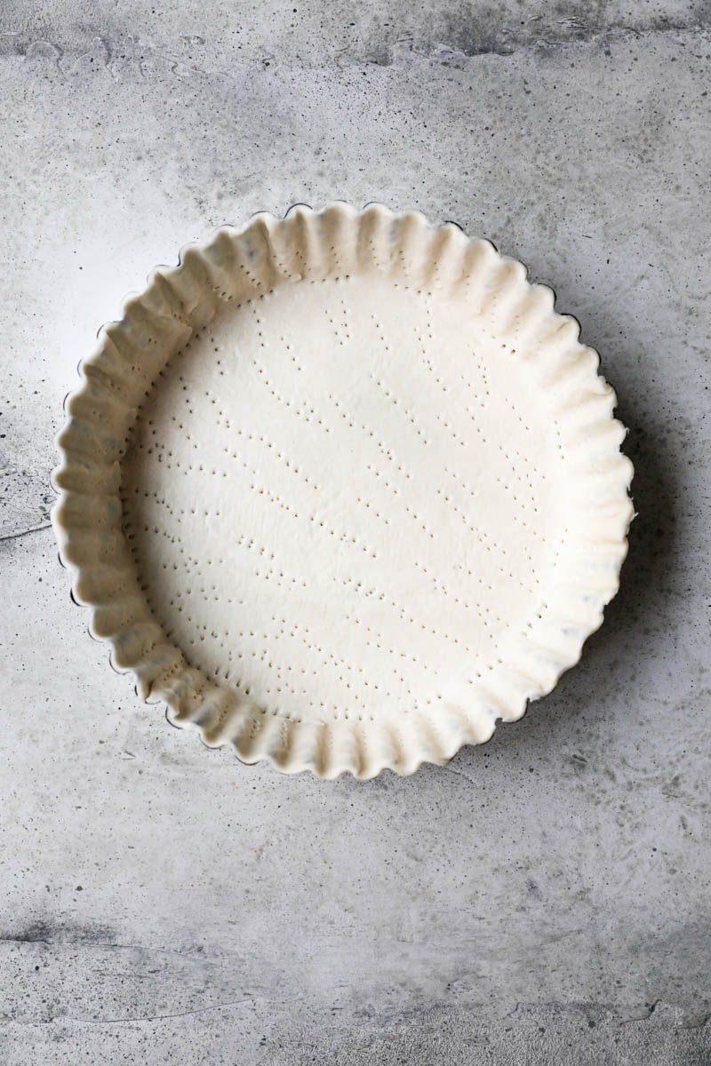 The tart tin lined with the quiche crust ready to bake.