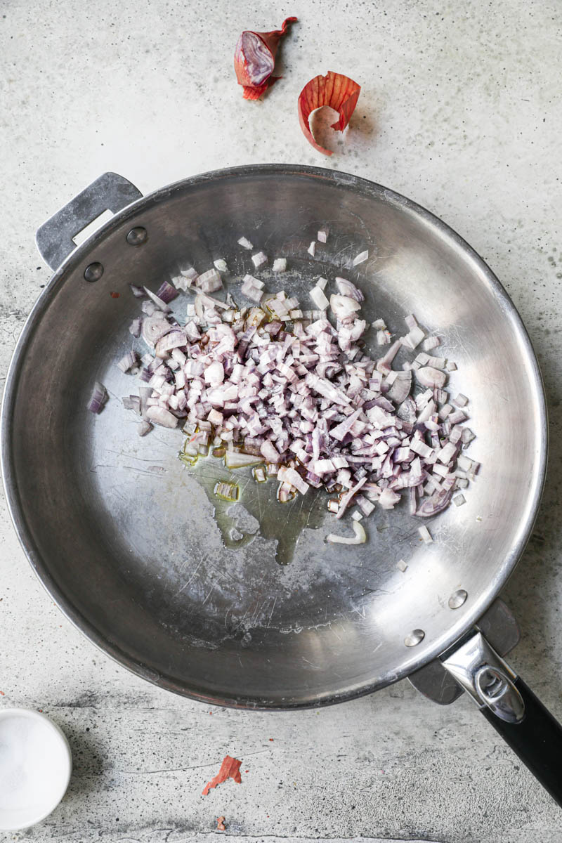 Chopped shallots on a pan with a dollop of olive oil.